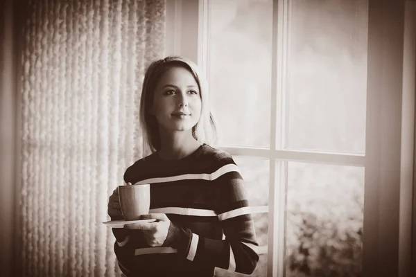 Menina com xícara de café ficar perto da janela — Fotografia de Stock