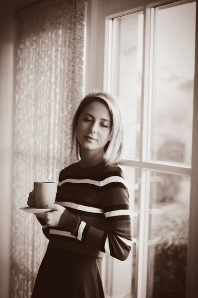 Menina com xícara de café ficar perto da janela — Fotografia de Stock