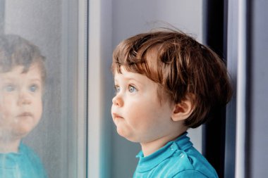 çocuğun Pencerenin kenarında duran ve araştırıyor