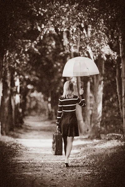 Girl with umbrella and suitcase in autumn park — Stock Photo, Image