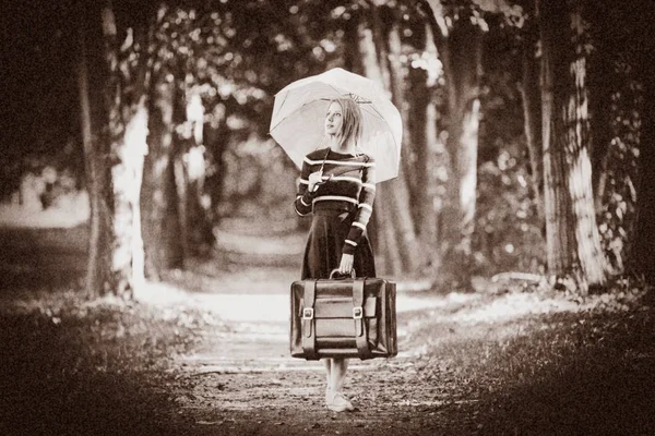 Дівчина з парасолькою і валіза в осінньому парку — стокове фото