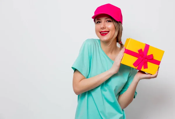 ピンクの帽子と白い背景の上の休日プレゼント ボックスの青い シャツの美しい少女 — ストック写真