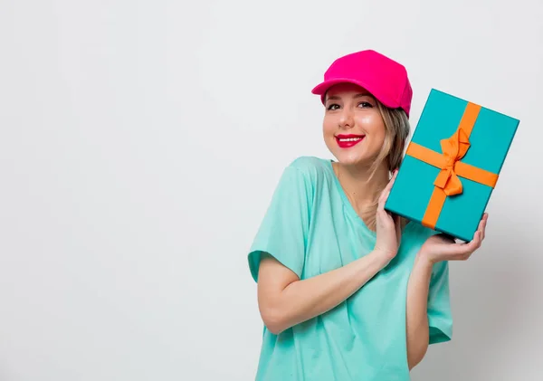 美丽的年轻女孩在粉红色的帽子和蓝色的 T恤与假日礼物箱子在白色背景 — 图库照片