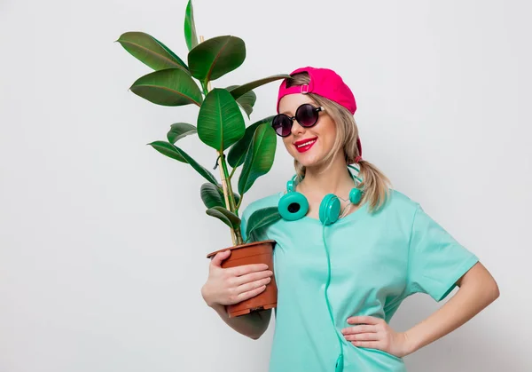 ピンクの帽子と白い背景の上の緑の植物で青い シャツの美しい少女 — ストック写真