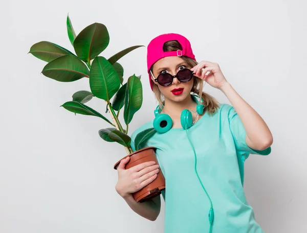 ピンクの帽子と白い背景の上の緑の植物で青い シャツの美しい少女 — ストック写真