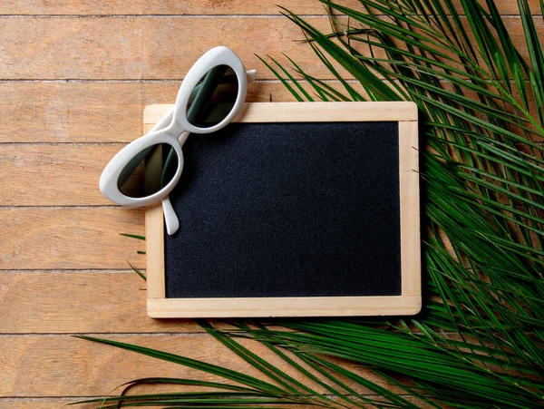 Óculos de sol com quadro-negro e ramo de palmeira — Fotografia de Stock