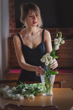 siyah elbiseli kız beyaz gül bir vazo içinde onları koymadan önce tutuyor