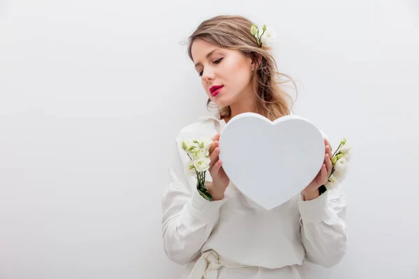 Femme avec des roses blanches tenant une boîte cadeau en forme de coeur . — Photo