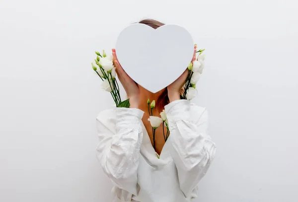 Donna con rose bianche in possesso di una scatola regalo a forma di cuore . — Foto Stock