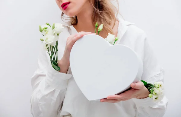 Mujer con rosas blancas sosteniendo una caja de regalo en forma de corazón . — Foto de Stock