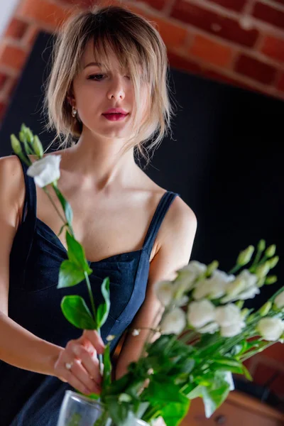 Chica en un vestido negro está sosteniendo rosas blancas antes de ponerlos en un jarrón — Foto de Stock