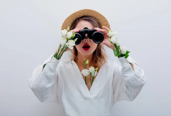 Kvinna med vita rosor i ärmar med kikare letar efter något — Stockfoto