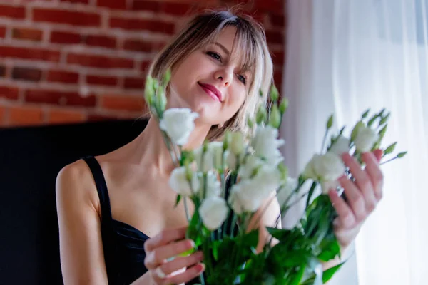 Menina em um vestido preto está segurando rosas brancas antes de colocá-los em um vaso — Fotografia de Stock