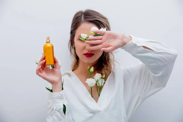 Mujer con rosas blancas sosteniendo un perfume — Foto de Stock