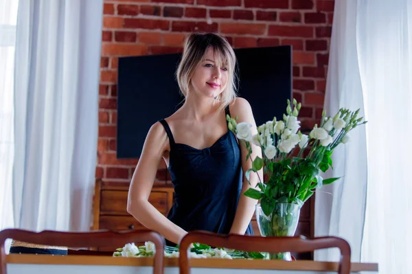 Fille dans une robe noire tient des roses blanches avant de les mettre dans un vase — Photo