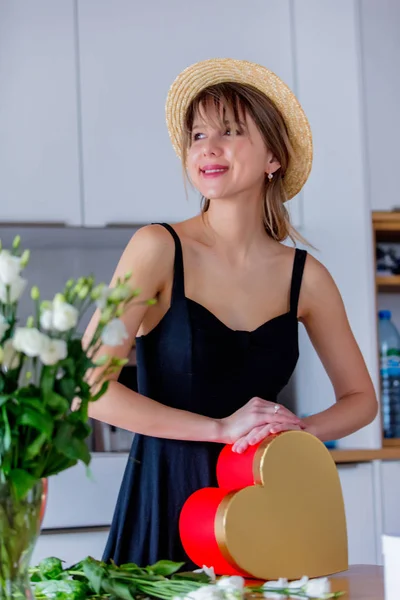 Mulher perto de rosas brancas buquê em um vaso e caixa de presente — Fotografia de Stock