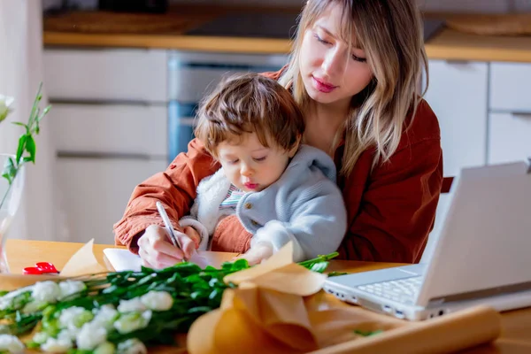 Mother with a child trying to working as a florist businesswoman — Stock Photo, Image