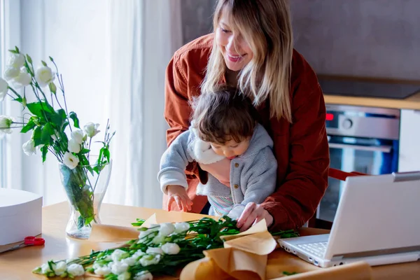 Mother with a child trying to working as a florist businesswoman — Stock Photo, Image