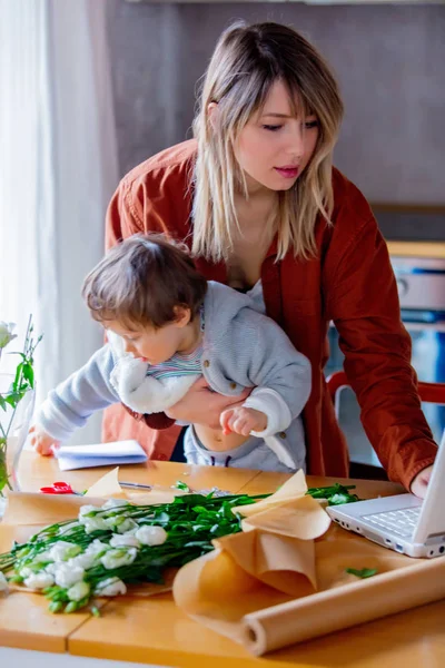 Mother with a child trying to working as a florist businesswoman — Stock Photo, Image