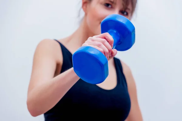 Beautiful adult girl holding a blue dumbbell — Stock Photo, Image