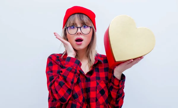 Vrouw in rood shirt en hoed houden de doos van de gift van hart vorm — Stockfoto