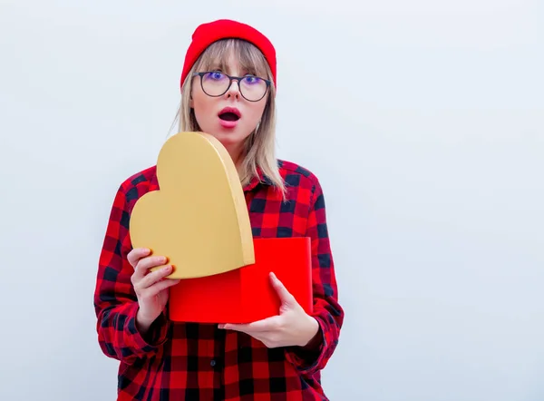Femme en chemise rouge et chapeau tenant boîte cadeau en forme de coeur — Photo