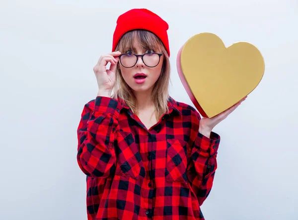 Woman in red shirt and hat holding heart shape gift box — Stock Photo, Image