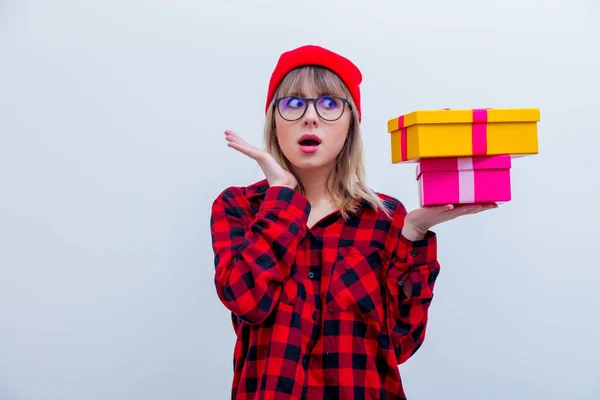 Mulher em camisa vermelha e chapéu segurando caixas de presente de férias — Fotografia de Stock