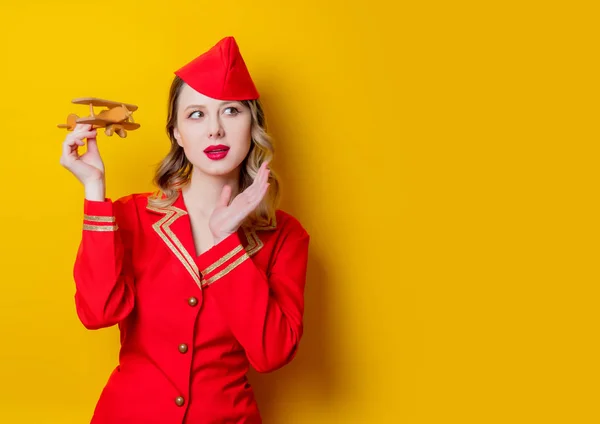 Charming vintage stewardess wearing in red uniform with airplane — Stock Photo, Image