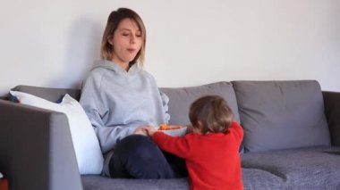 Anne ile oğlu elinde uzaktan kumanda ve Tv izlerken