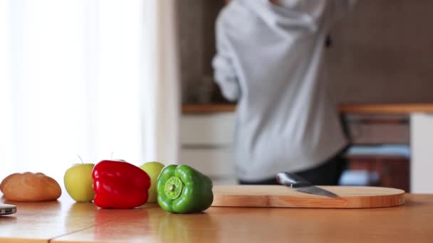 Zöld és piros paprika az apple egy kést egy fa asztal — Stock videók