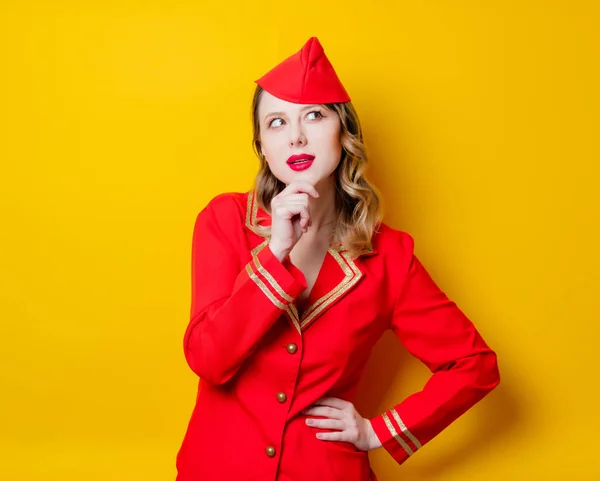 赤い制服を着て魅力的なヴィンテージ スチュワーデスの肖像画 黄色の背景に分離 — ストック写真