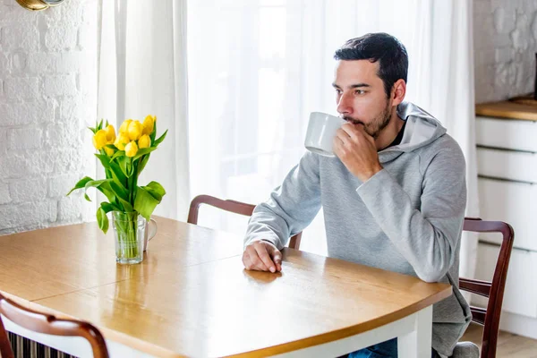 Man sitter vid bordet med kopp kaffe eller te — Stockfoto