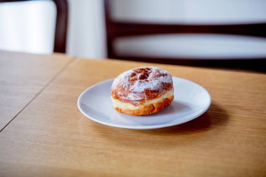 Ahşap mutfak masasında üzerinde beyaz tabakta donut