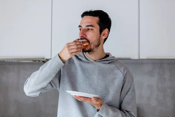 Mann isst Donut beim Frühstück in der Küche — Stockfoto