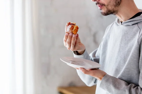 Mann isst Donut beim Frühstück in der Küche — Stockfoto