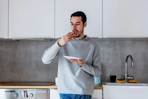 Mann isst Donut beim Frühstück in der Küche — Stockfoto