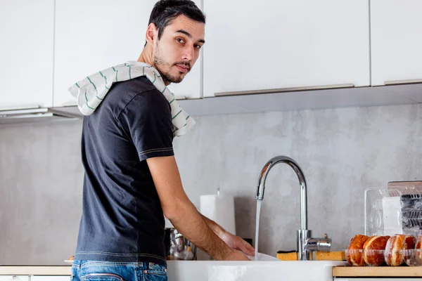 Hombre joven en camisa negra cocinando en la cocina en casa . —  Fotos de Stock