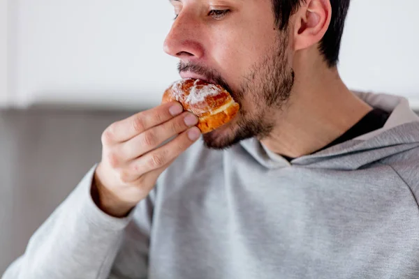 Man eating donut on breakfast at kitchen — Stock Photo, Image