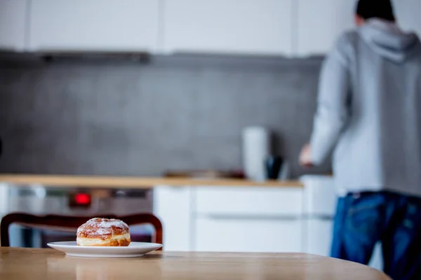 Donut op houten tafel in de keuken en de man op de achtergrond — Stockfoto