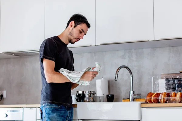 Hombre joven en camisa negra cocinando en la cocina en casa . —  Fotos de Stock