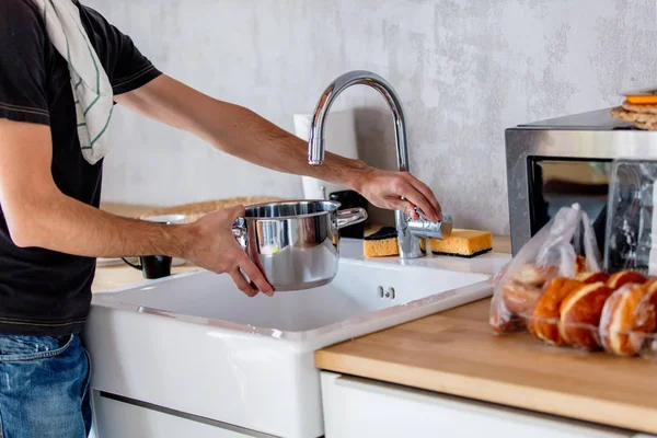 Hombre joven en camisa negra cocinando en la cocina en casa . —  Fotos de Stock