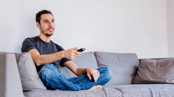 Homem com controle remoto no sofe assistindo TV — Fotografia de Stock
