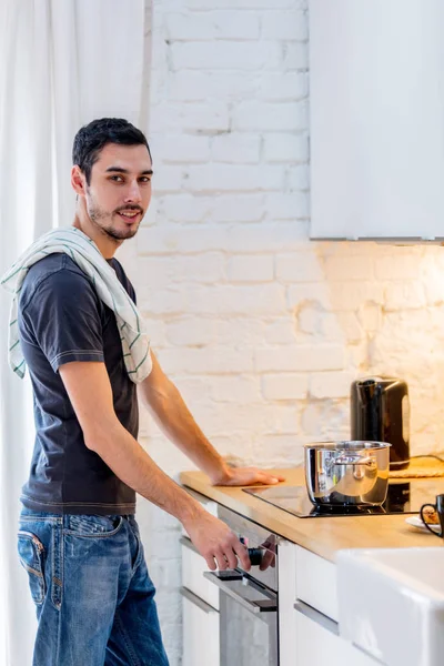 Junger Mann in schwarzem Hemd kocht zu Hause in Küche. — Stockfoto