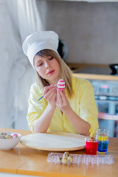 Vrouwtje als chef-kok schilderij eieren voor de paasvakantie — Stockfoto