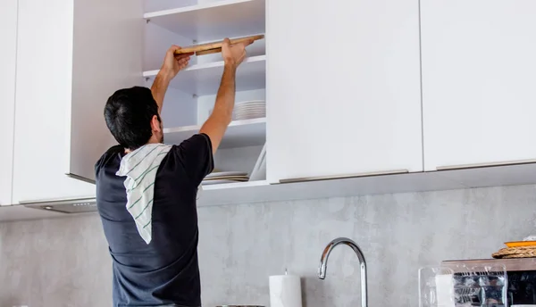 Jovem de camisa preta cozinhar na cozinha em casa . — Fotografia de Stock