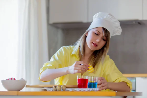 Vrouwtje als chef-kok schilderij eieren voor de paasvakantie — Stockfoto