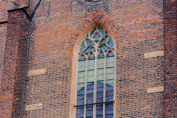 Old decorated cathedral stained glass window and brick wall — Stock Photo, Image