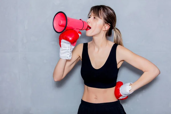 Jovem mulher em luvas de boxe com alto-falante — Fotografia de Stock