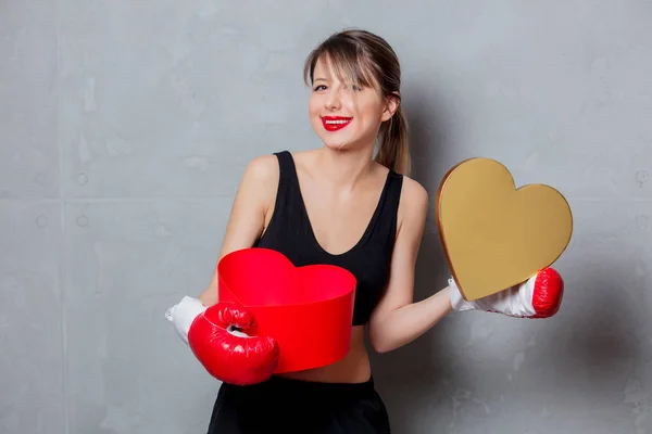 Vrouw in bokshandschoenen met hart vorm gift box in handen — Stockfoto